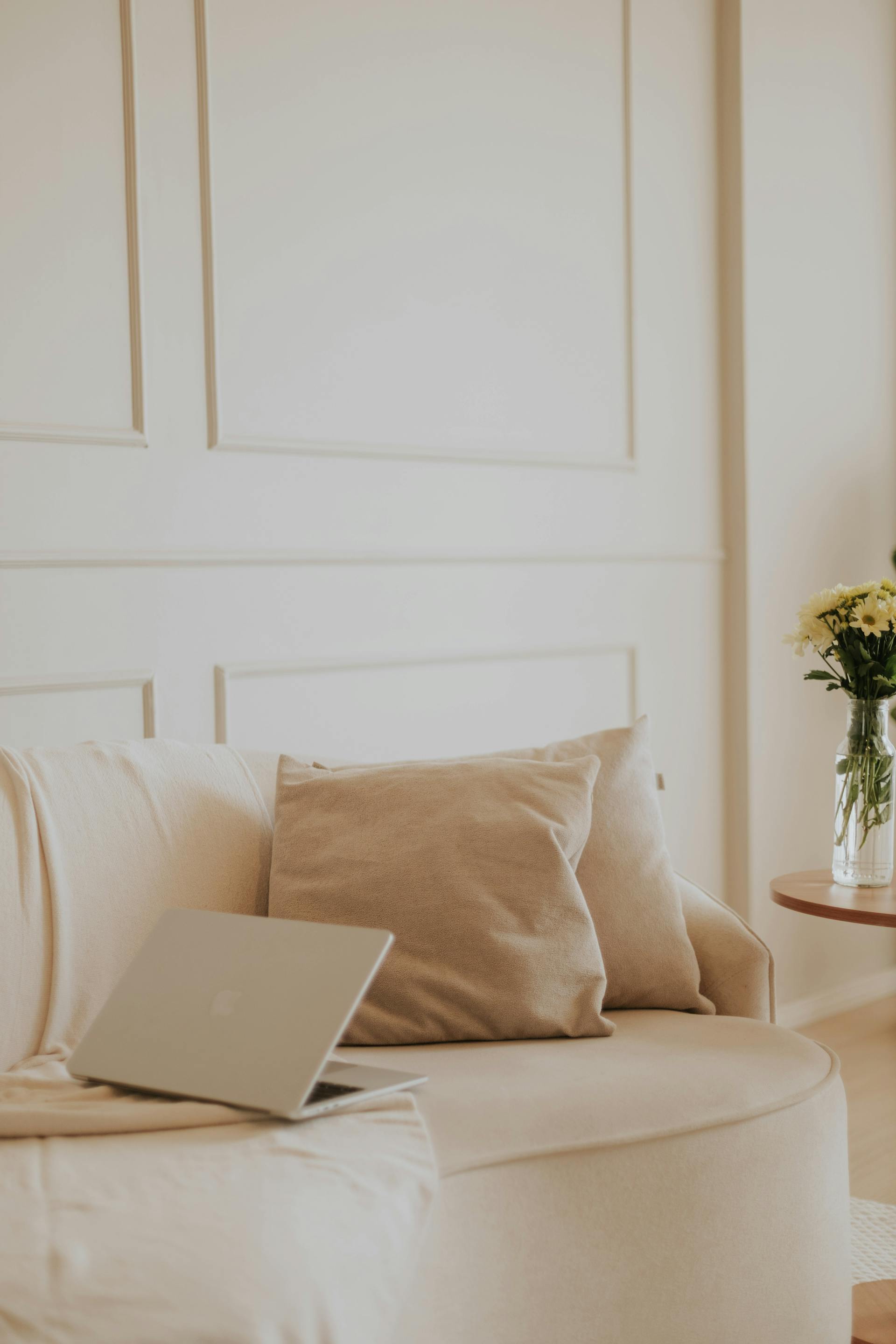 Moderner Remote-Arbeitsplatz mit Laptop auf einem beigen Sofa; repräsentiert die agile Webentwicklung für Next.js Projekte von überall aus.